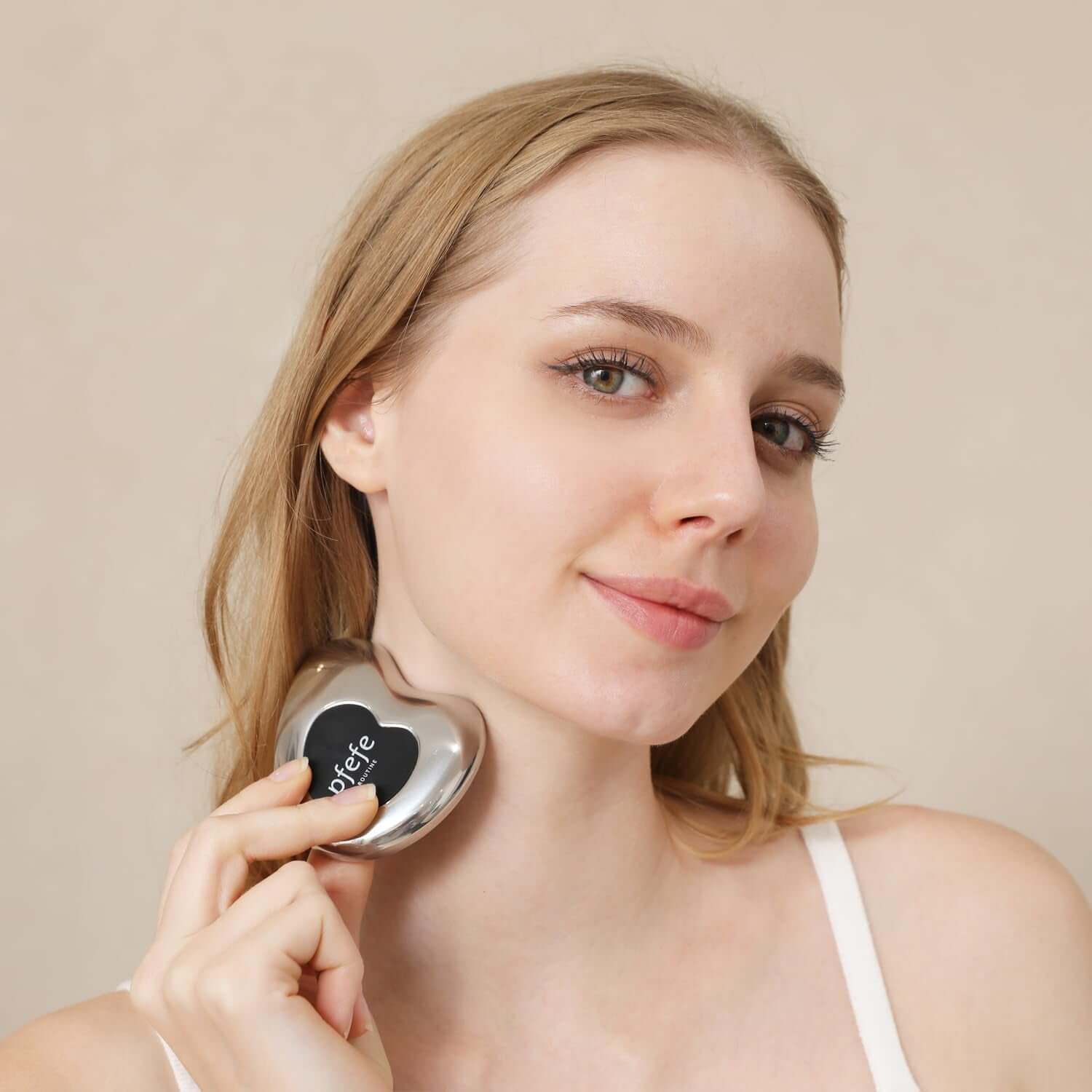 Woman using stainless steel cryo gua sha tool for facial beauty and skin care.